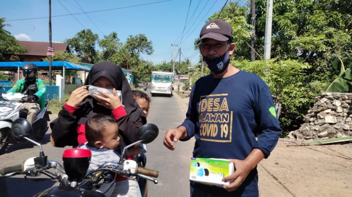 Aparat desa sedang bagi Masker di jalan.