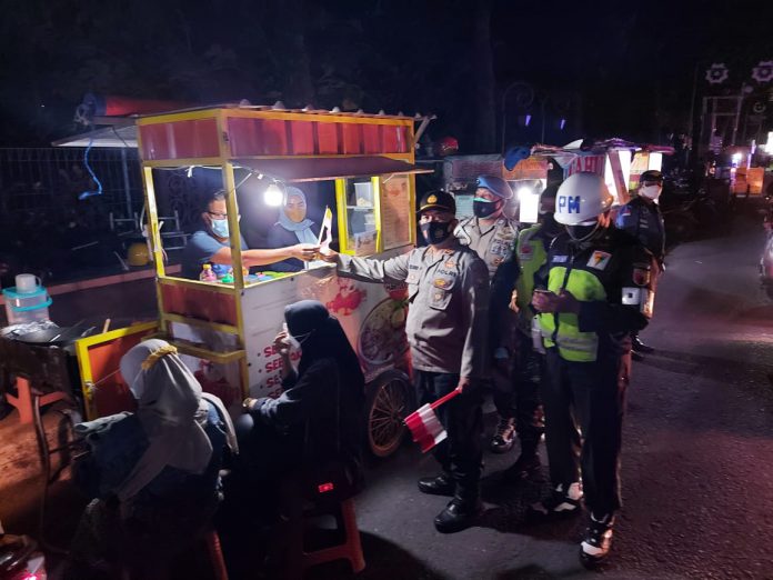 Personil gabungan terdiri Polres Jombang, Kodim 0814 dan Satpol PP Pemkab Jombang melaksanakan operasi yustisi sekaligus membagikan bendera merah putih kepada pedagang kaki lima (PKL).